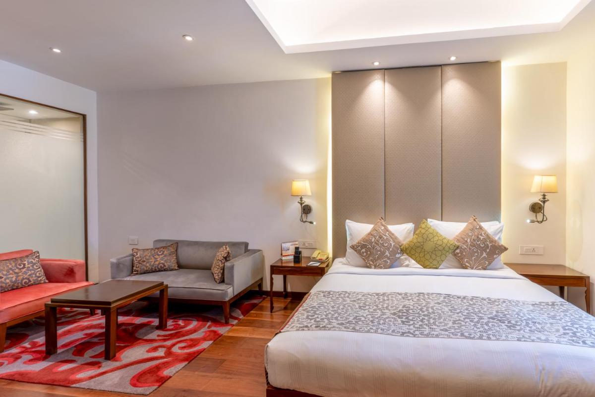 a bedroom with a king sized bed and a couch at Pride Plaza Hotel, Kolkata in Kolkata