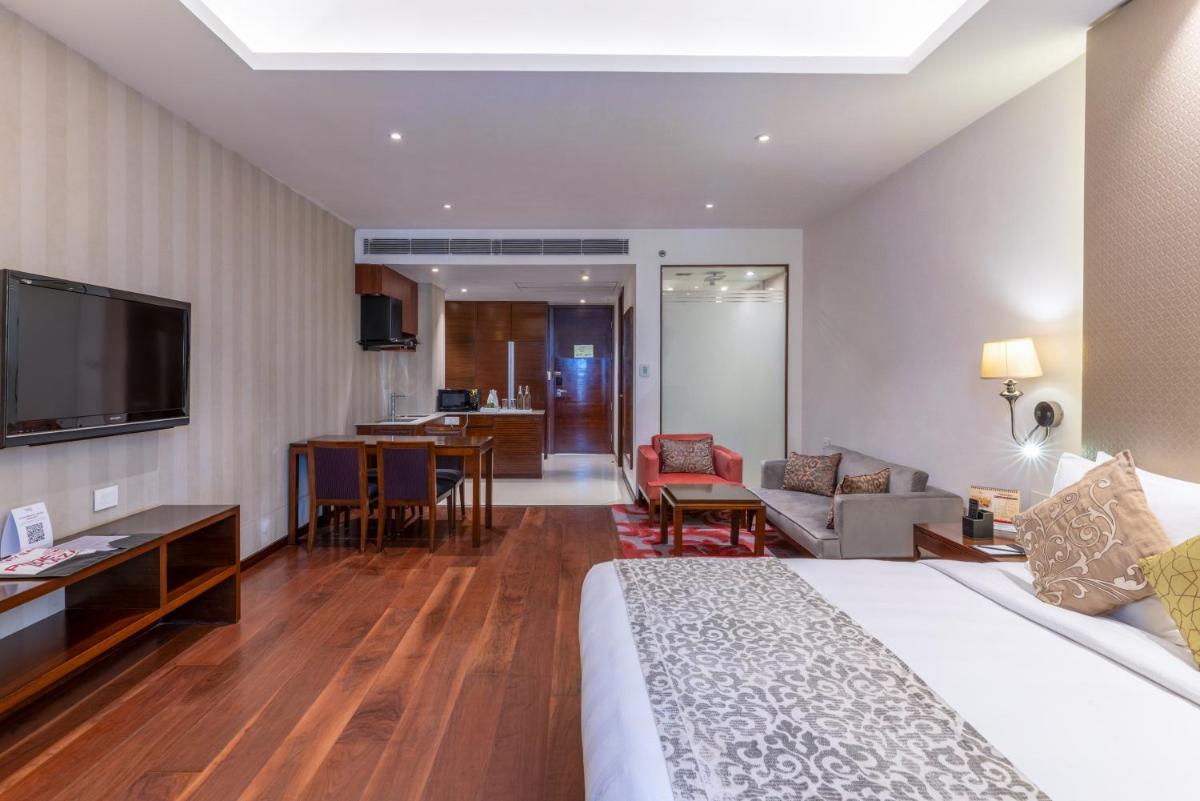 a hotel room with a bed and a living room at Pride Plaza Hotel, Kolkata in Kolkata