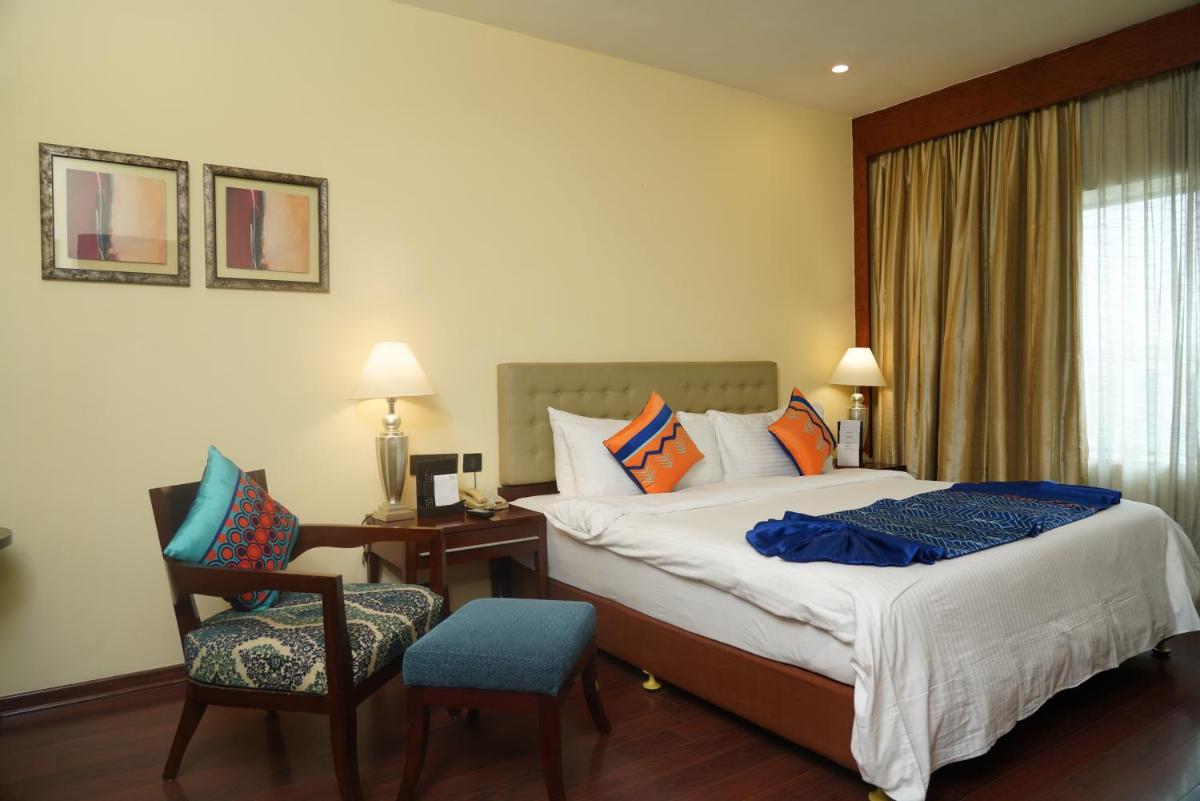 a hotel room with a bed and a chair at Fortune Select JP Cosmos, Bengaluru - Member ITC Hotels' Group in Bengaluru