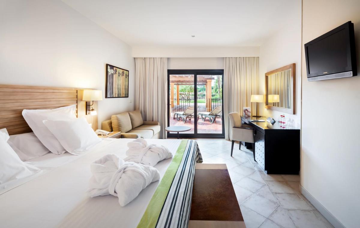 Una habitación de hotel con una cama grande y un escritorio. en Barceló Punta Umbría Beach Resort, en Punta Umbría