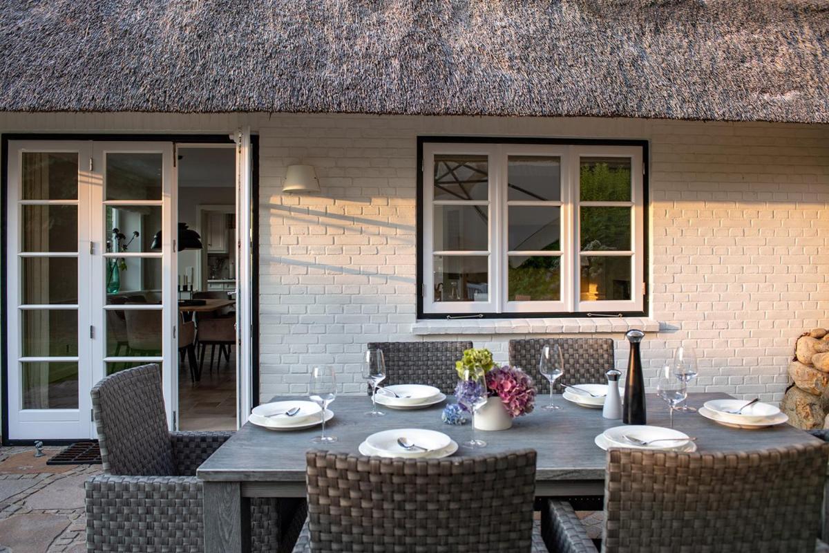 einen Holztisch mit Tellern und Weingläsern auf einer Terrasse in der Unterkunft Benen-Diken-Hof in Keitum einen Holztisch mit Tellern und Weingläsern auf einer Terrasse in der Unterkunft Benen-Diken-Hof in Keitum