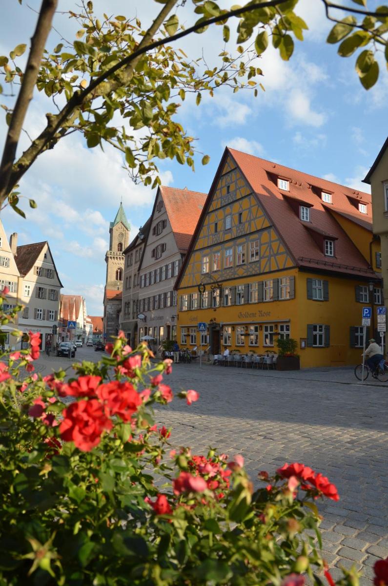 eine Stadtstraße mit Gebäuden und roten Blumen in der Unterkunft HOTEL & SPA Goldene Rose in Dinkelsbühl