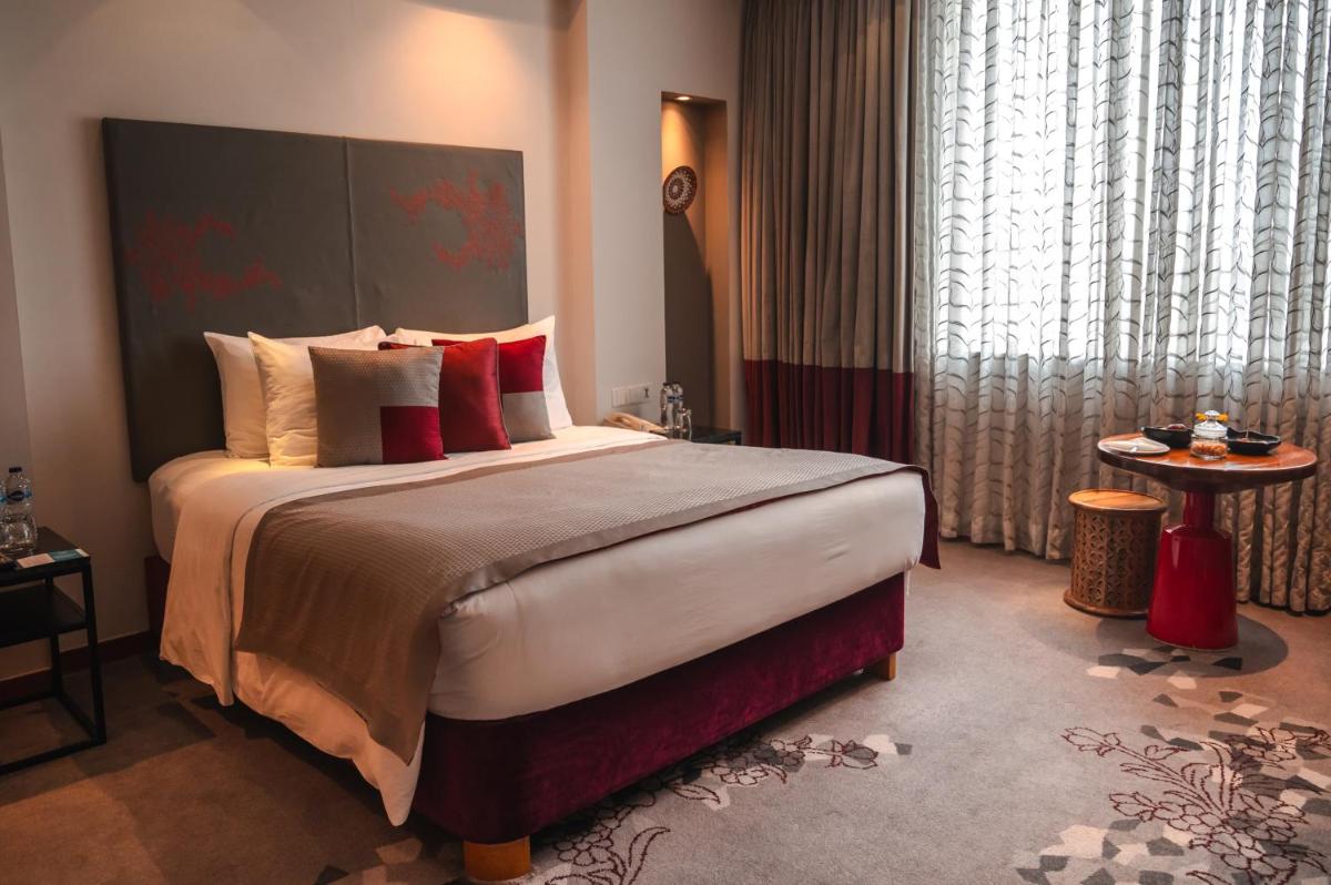 a hotel room with a large bed with red pillows at The Park Kolkata in Kolkata