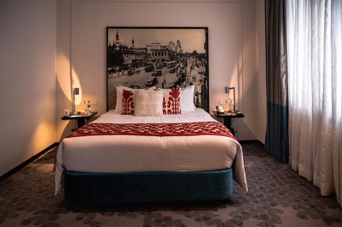a bedroom with a large bed with a painting on the wall at The Park Kolkata in Kolkata