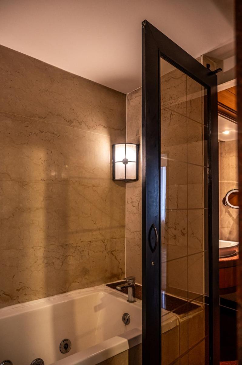 a bathroom with a tub and a light on the wall at The Park Kolkata in Kolkata