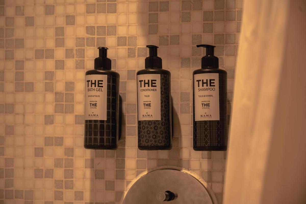 four bottles on a wall above a toilet in a bathroom at The Park Kolkata in Kolkata