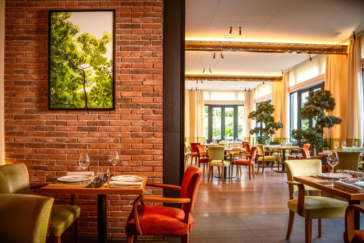 un restaurant avec des tables et des chaises et un mur de briques dans l'établissement Domaine les Crayères, à Reims