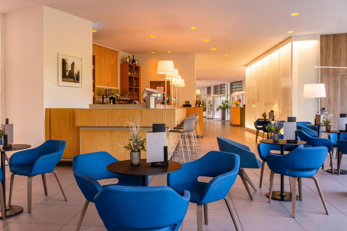 un restaurant avec des tables et des chaises bleues dans l'établissement Eau Thermale Avène l'hôtel, à Avène