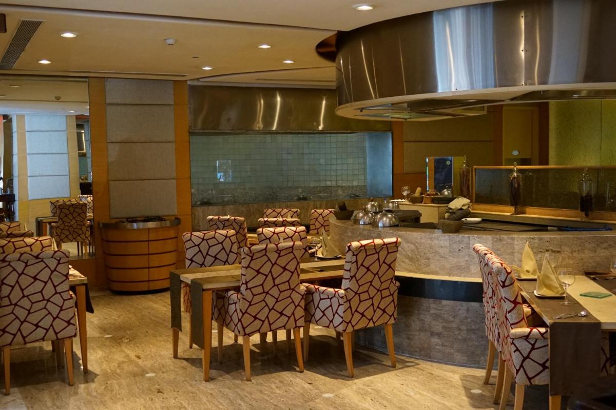 a restaurant with tables and chairs and a kitchen at Taj Chandigarh in Chandīgarh