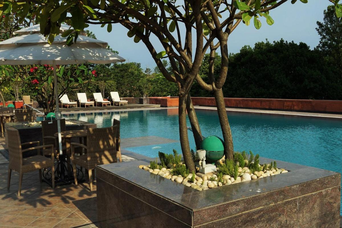 a swimming pool with a table and a green ball between two trees at Taj Chandigarh in Chandīgarh