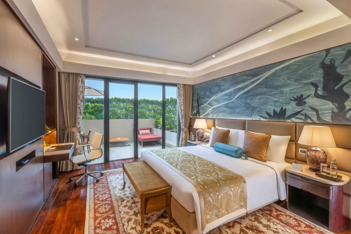 a bedroom with a large bed and a large painting on the wall at The Leela Ambience Convention Hotel Delhi in New Delhi
