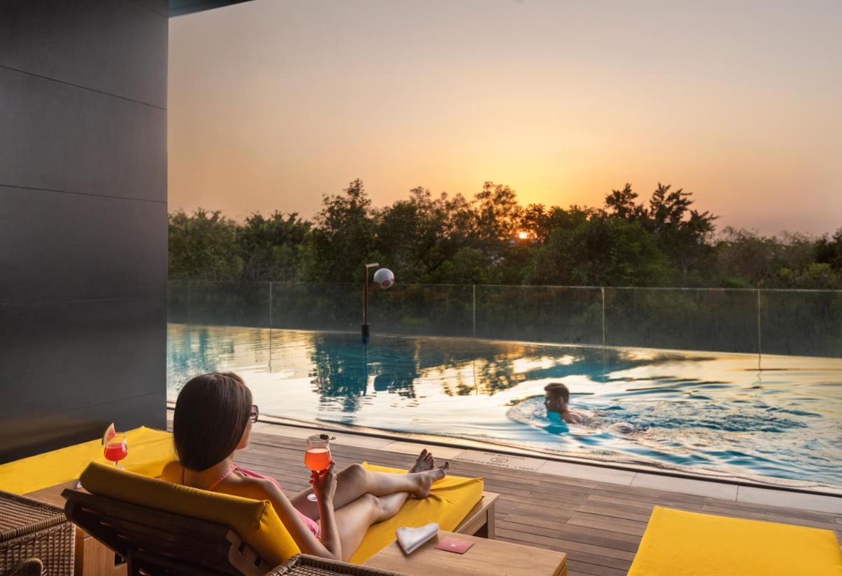 two people in a swimming pool with the sunset at Trident Hyderabad in Hyderabad