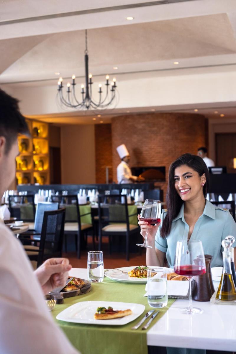 a woman sitting at a table with a glass of wine at Trident Hyderabad in Hyderabad