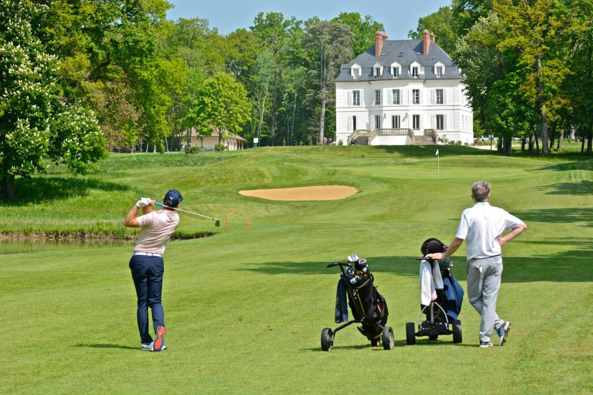 un groupe de personnes jouant au golf devant une maison dans l'établissement Domaine Du Roncemay - Hôtel, Restaurants, Spa & Golf, à Aillant-sur-Tholon