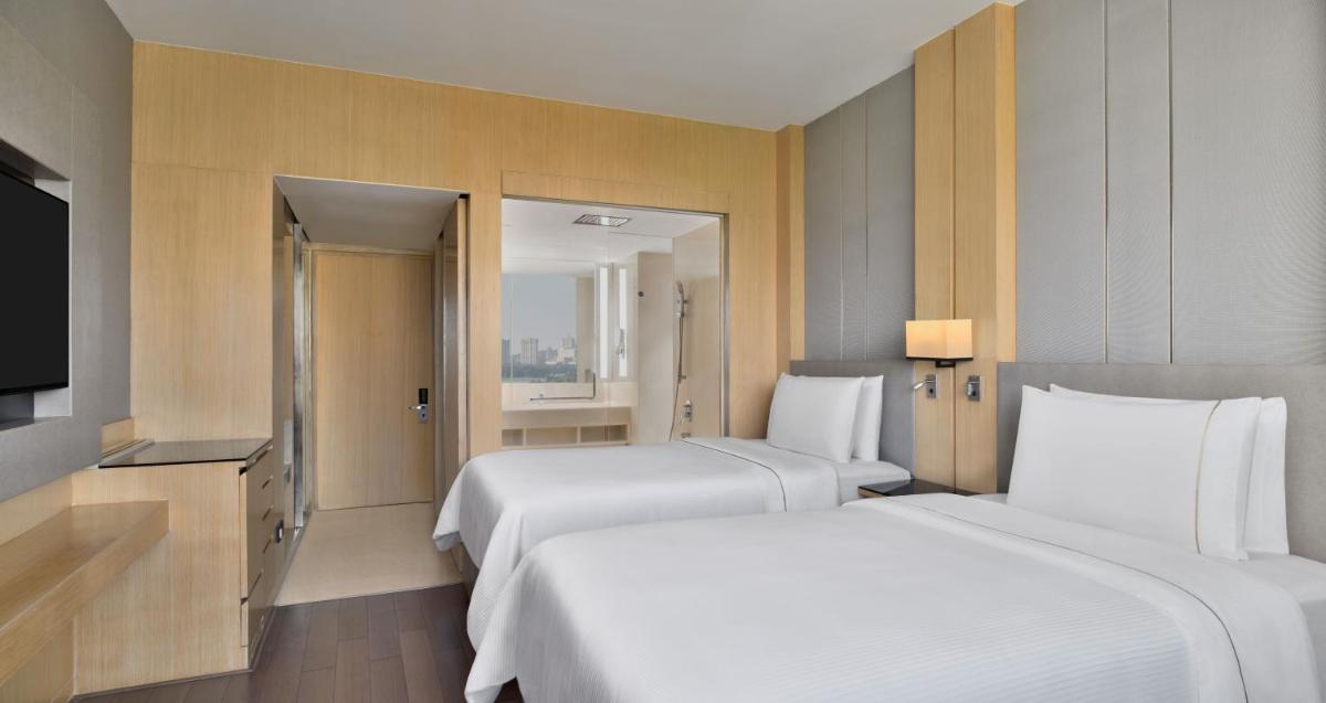 a hotel room with two beds and a television at The Westin Mumbai Powai Lake in Mumbai