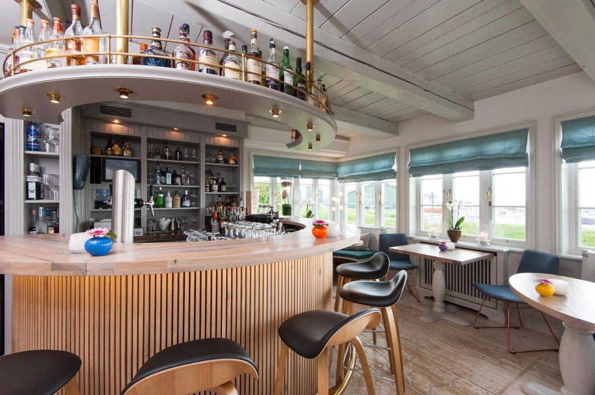 eine Bar in einem Restaurant mit Stühlen und Tischen in der Unterkunft Hotel Fährhaus in Munkmarsch