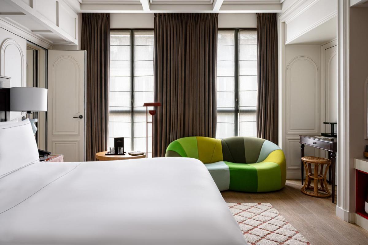 une chambre d'hôtel avec un lit et une chaise verte dans l'établissement Experimental Marais, à Paris
