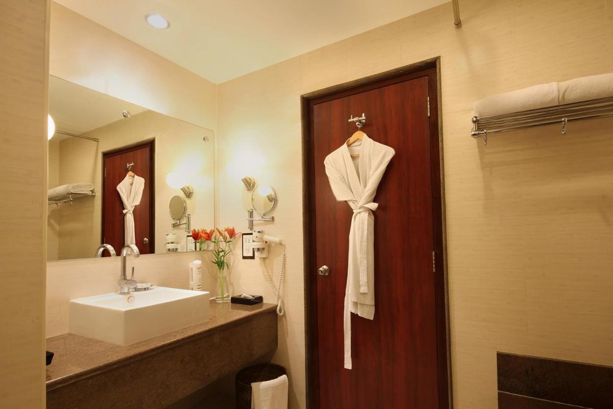 a bathroom with a sink and a robe on a door at Fortune Select JP Cosmos, Bengaluru - Member ITC Hotels' Group in Bengaluru