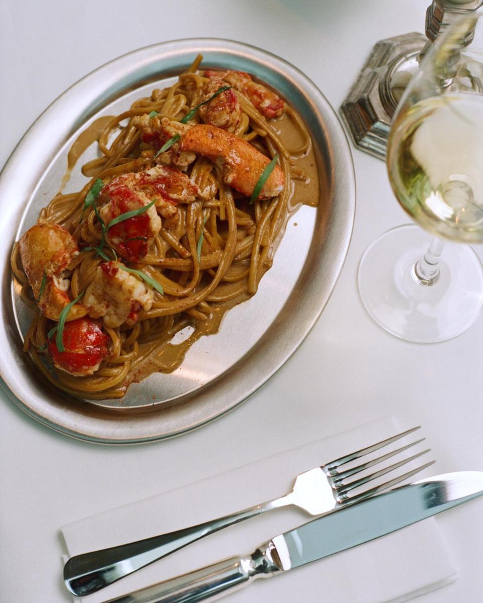 une assiette de nourriture sur une table à côté d'un verre de vin dans l'établissement Experimental Marais, à Paris