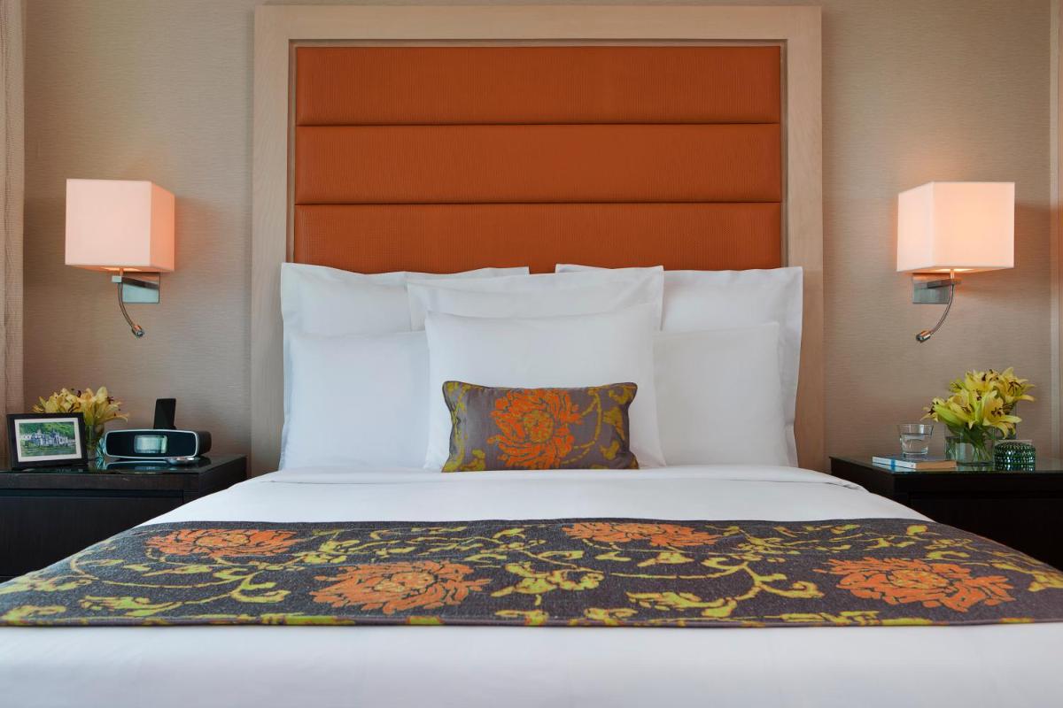 a bed in a hotel room with two lamps at Marriott Executive Apartment - Lakeside Chalet, Mumbai in Mumbai