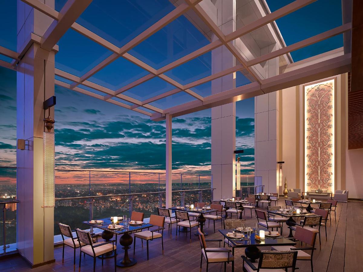 a restaurant with tables and chairs with a view at Shangri-La Bengaluru in Bengaluru a restaurant with tables and chairs with a view at Shangri-La Bengaluru in Bengaluru