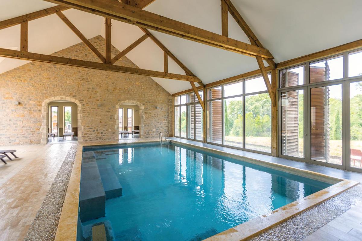 une grande piscine intérieure avec fenêtres et eau bleue dans l'établissement Belambra Clubs Résidence Rocamadour - Les Portes De Dordogne, à Alvignac 19 autres photos