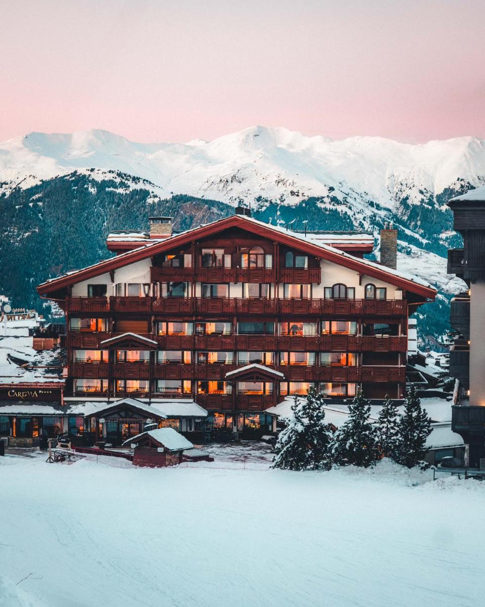 un grand bâtiment avec de la neige devant une montagne dans l'établissement Hotel Carlina, à Courchevel