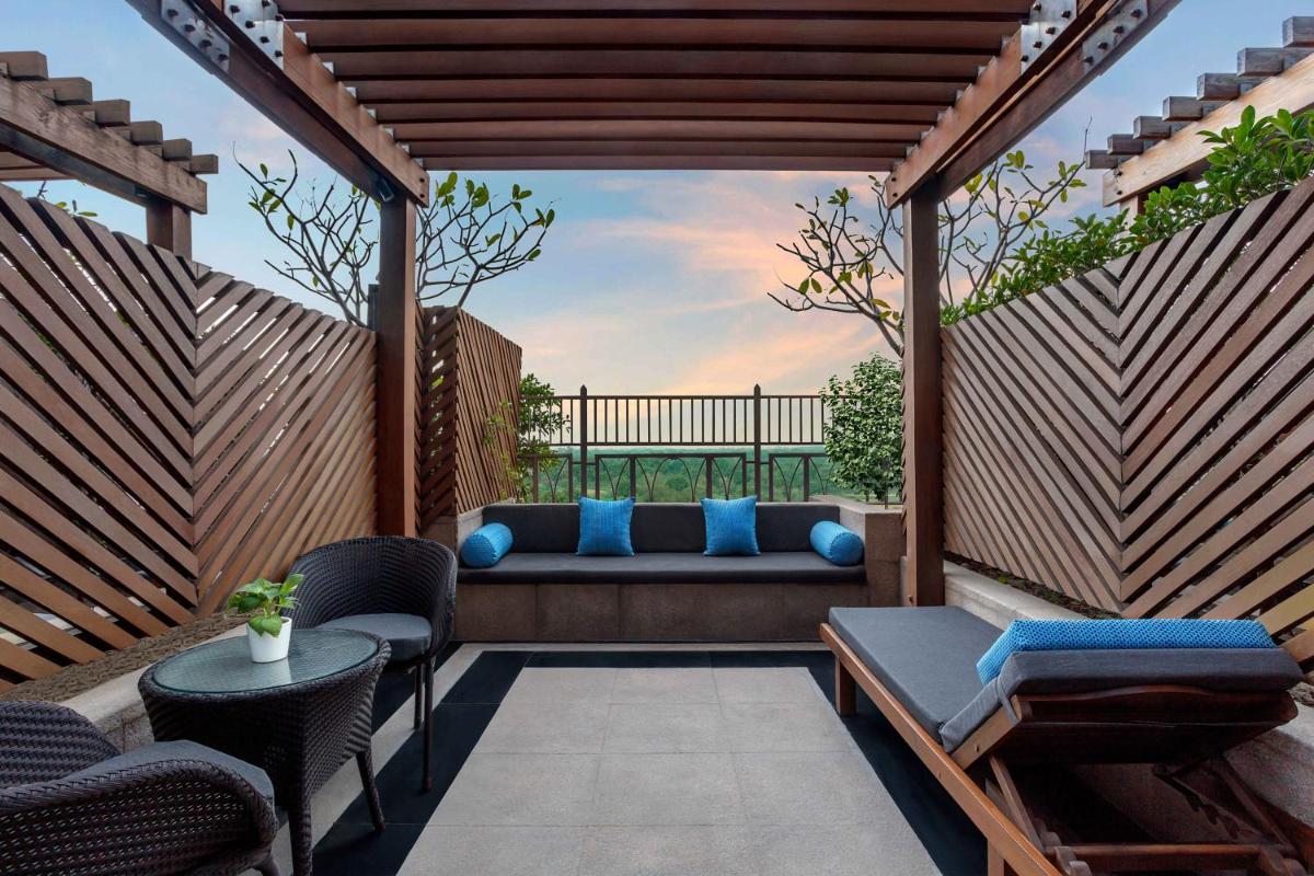 a pergola with a bench on a patio at The Leela Ambience Gurugram Hotel & Residences - The Luxury Urban Sanctuary in Gurgaon