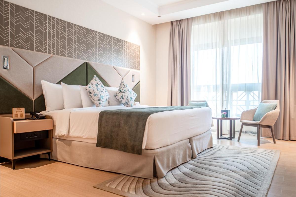 a hotel room with a bed and a large window at Barcelo Al Jaddaf, Dubai in Dubai