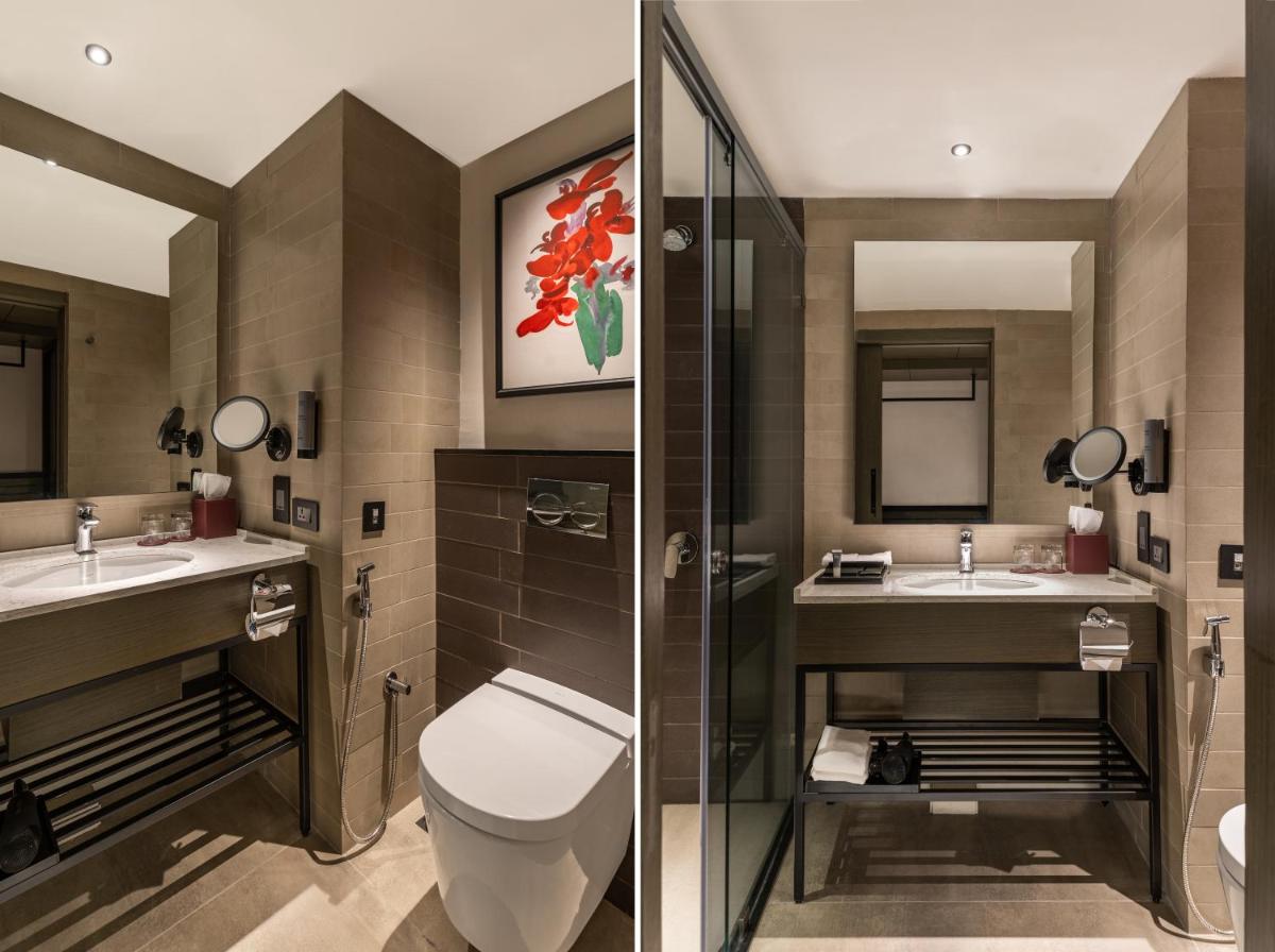 a bathroom with a toilet and two sinks and a shower at Parallel Hotel Udaipur, a member of Radisson Individuals in Udaipur