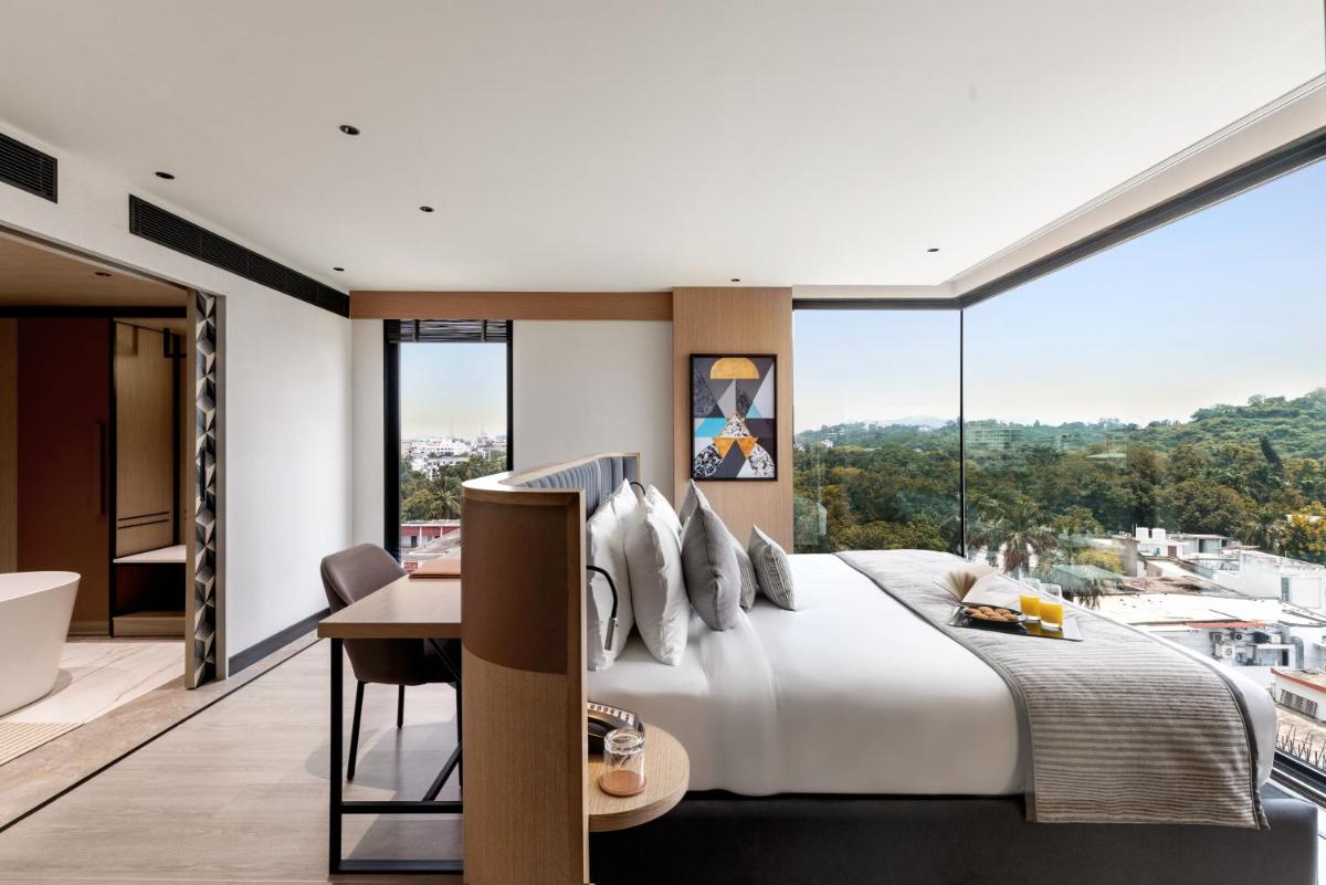 a bedroom with a large bed with a desk and a large window at Parallel Hotel Udaipur, a member of Radisson Individuals in Udaipur
