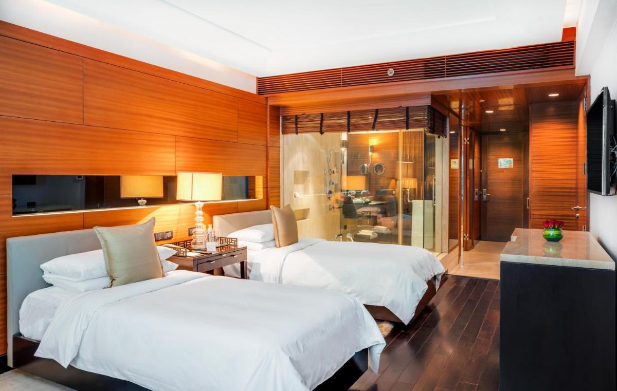 a hotel room with two beds and a bathroom at The Leela Ambience Gurugram Hotel & Residences - The Luxury Urban Sanctuary in Gurgaon