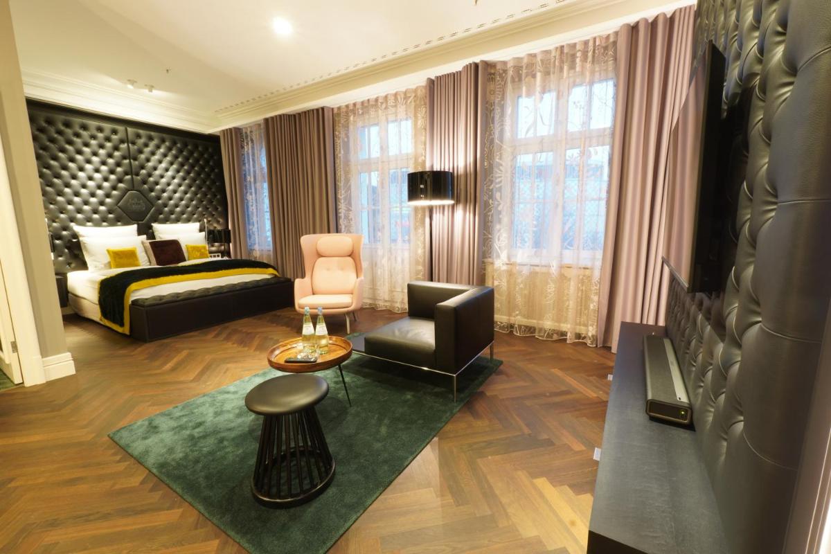 ein Hotelzimmer mit einem Bett und einem Stuhl in der Unterkunft Lumière Boutiquehotel im Fürstenhof Leipzig in Leipzig ein Hotelzimmer mit einem Bett und einem Stuhl in der Unterkunft Lumière Boutiquehotel im Fürstenhof Leipzig in Leipzig