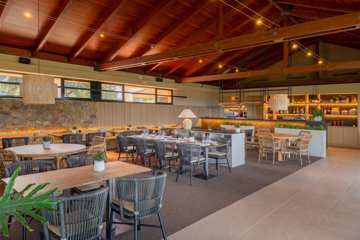 Un restaurante con mesas y sillas y un bar. en Hotel TorreMirona Golf & Spa, en Navata