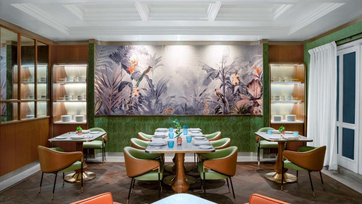 a dining room with tables and chairs and a painting at Hilton Mumbai International Airport Hotel in Mumbai