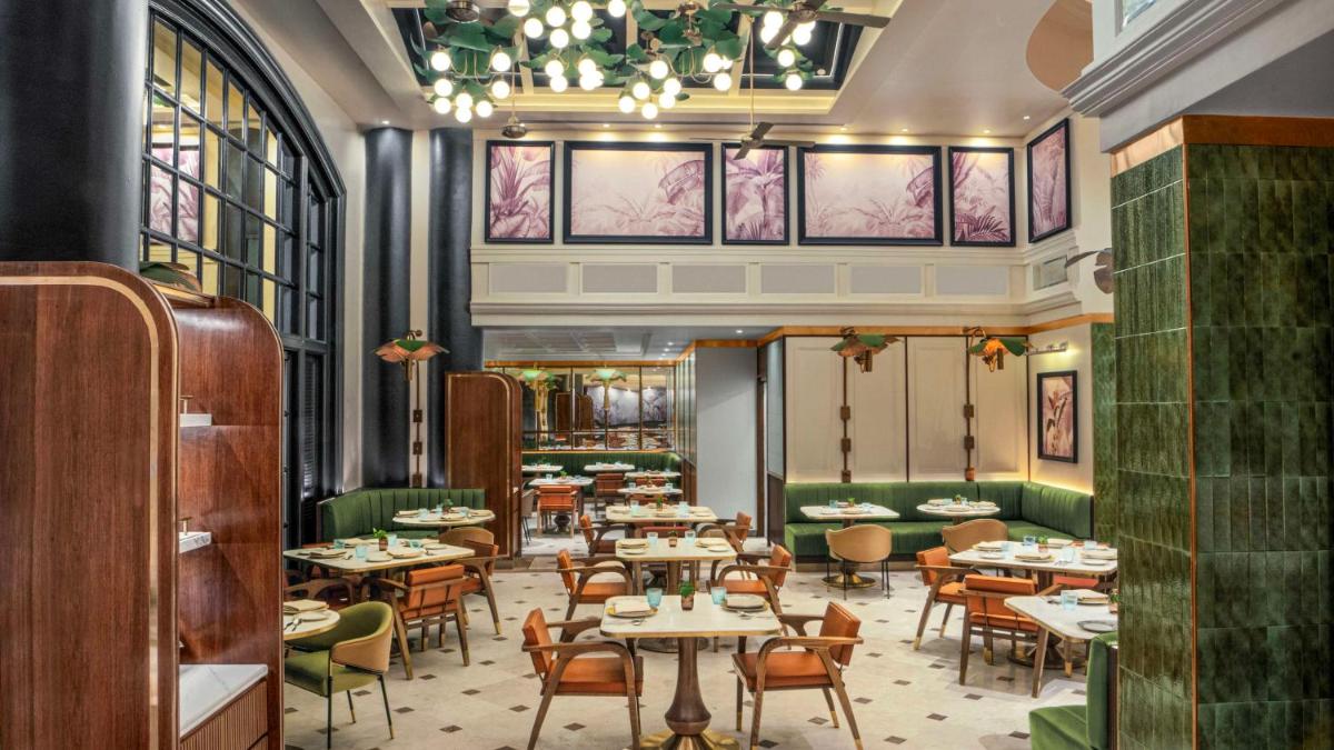 a restaurant with tables and chairs and windows at Hilton Mumbai International Airport Hotel in Mumbai