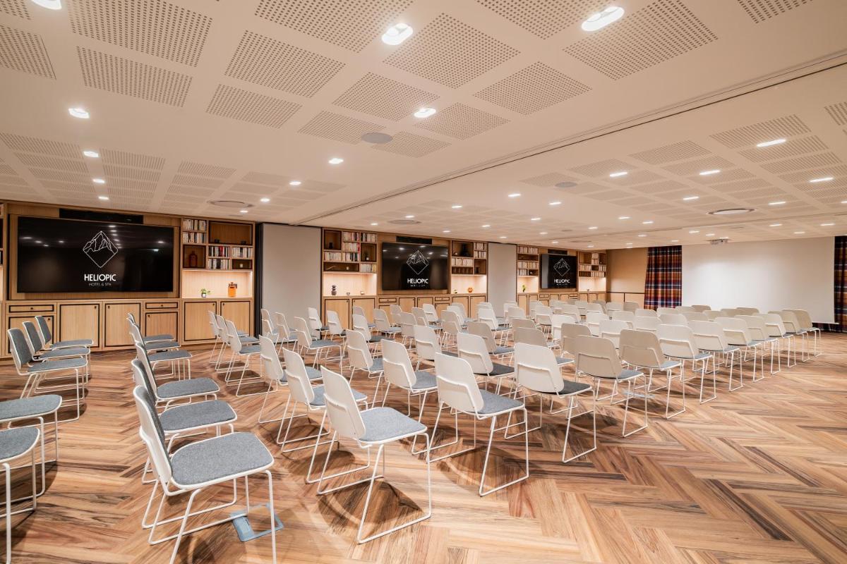 une salle de conférence avec des chaises blanches et un écran de projection dans l'établissement Heliopic Hotel & Spa, à Chamonix-Mont-Blanc 132 autres photos