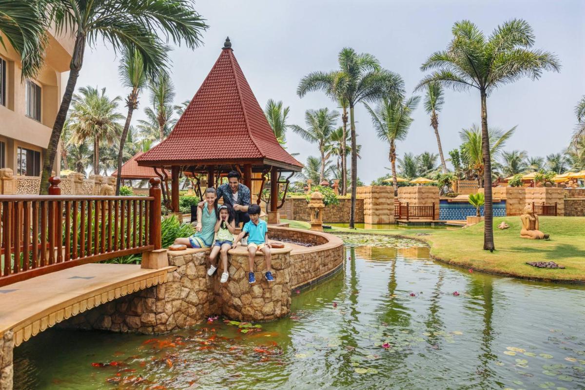 a group of people sitting on a bridge over a pond at a resort at JW Marriott Mumbai Juhu in Mumbai
