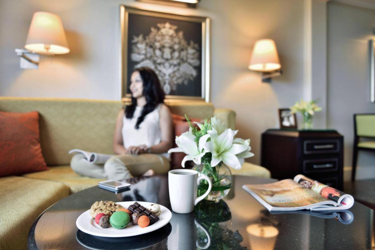a woman sitting on a couch in a living room at Marriott Executive Apartment - Lakeside Chalet, Mumbai in Mumbai