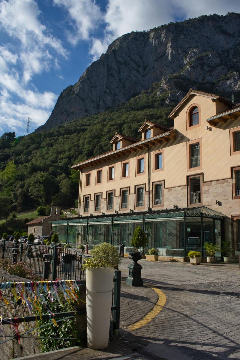 Un gran edificio con una montaña al fondo. en Hotel Balneario La Hermida, en La Hermida
