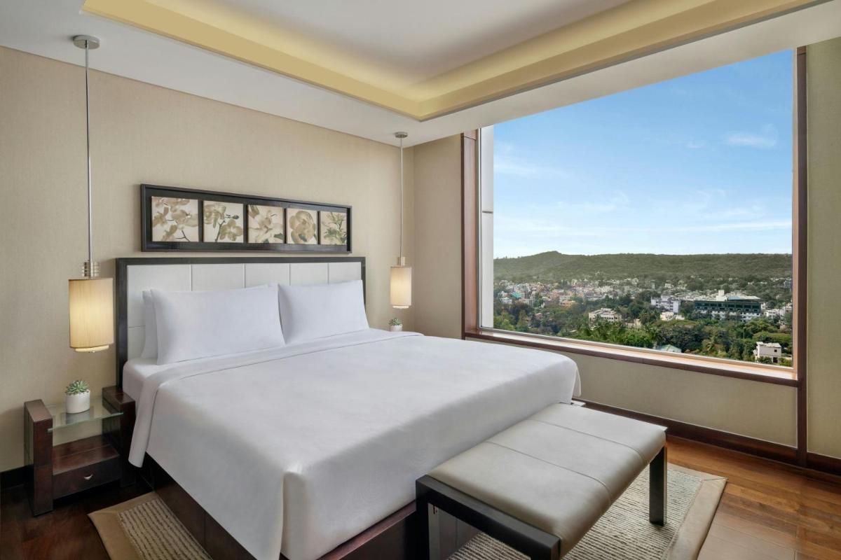 a bedroom with a large white bed and a large window at JW Marriott Pune in Pune