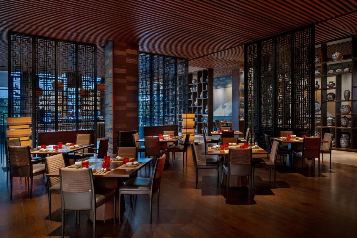 a dining room with tables and chairs and windows at JW Marriott Pune in Pune
