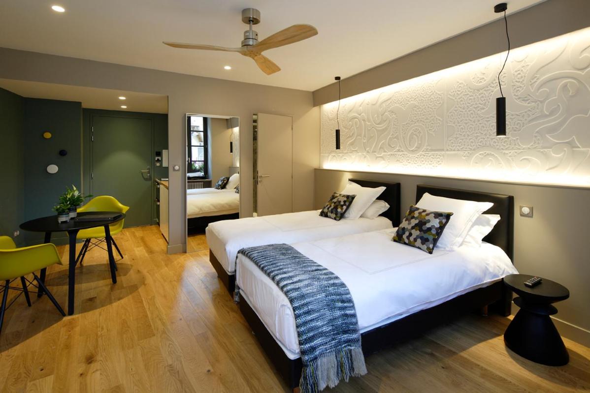 - 2 lits dans une chambre d'hôtel avec une table et des chaises dans l'établissement Les Maisons du Pont - Charme & Caractère, à Aubusson