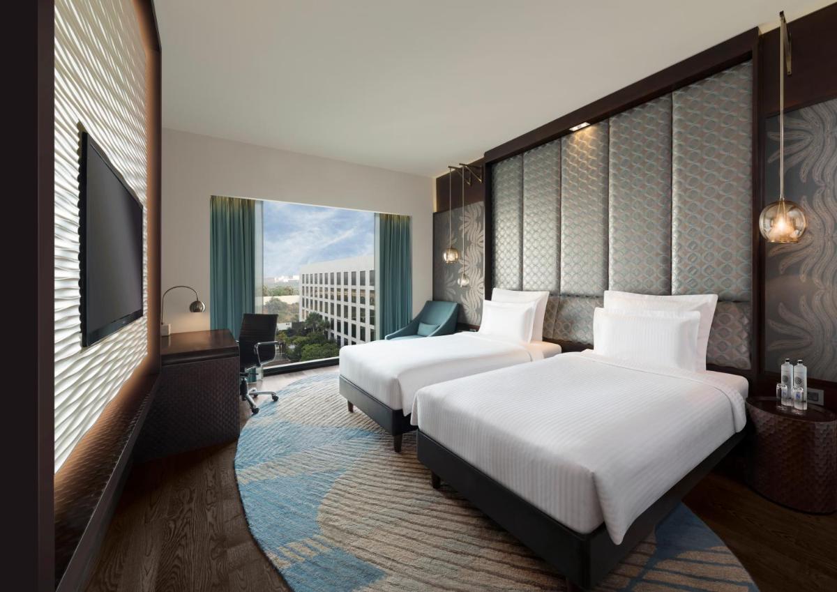 a hotel room with two beds and a window at Pullman New Delhi Aerocity in New Delhi a hotel room with two beds and a window at Pullman New Delhi Aerocity in New Delhi