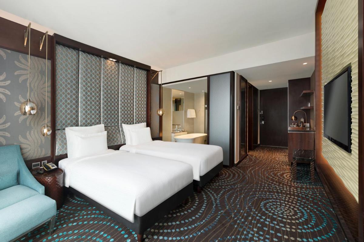 a hotel room with two beds and a couch at Pullman New Delhi Aerocity in New Delhi a hotel room with two beds and a couch at Pullman New Delhi Aerocity in New Delhi