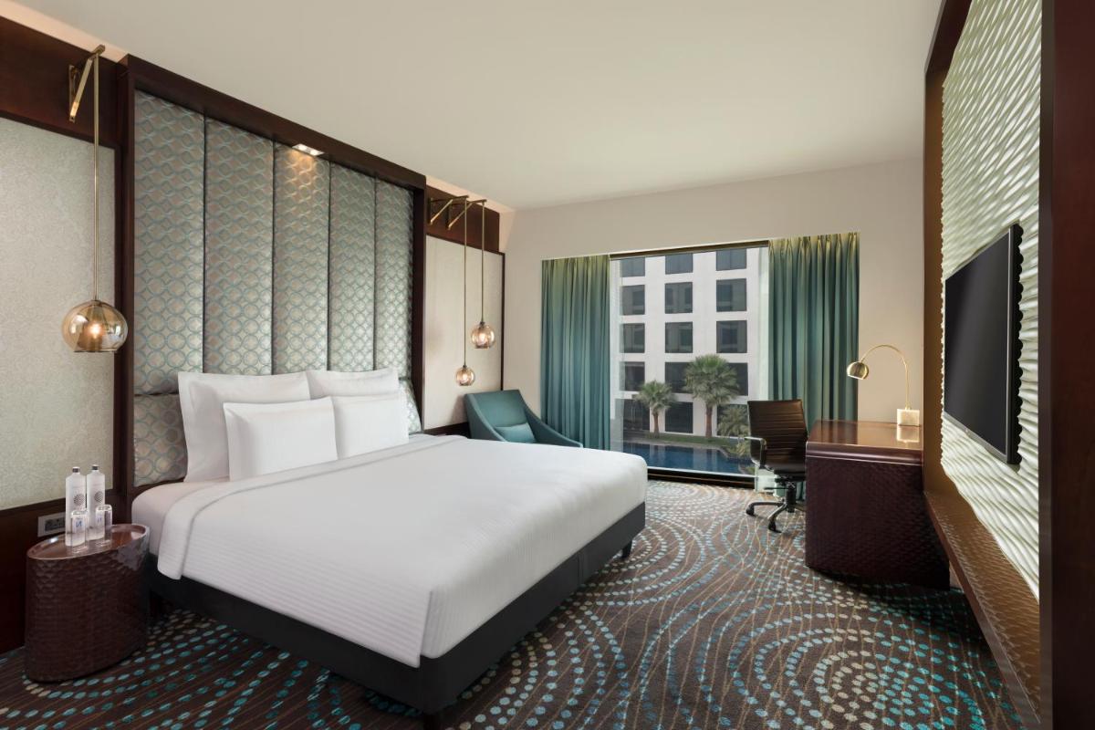 a hotel room with a large bed and a desk at Pullman New Delhi Aerocity in New Delhi a hotel room with a large bed and a desk at Pullman New Delhi Aerocity in New Delhi