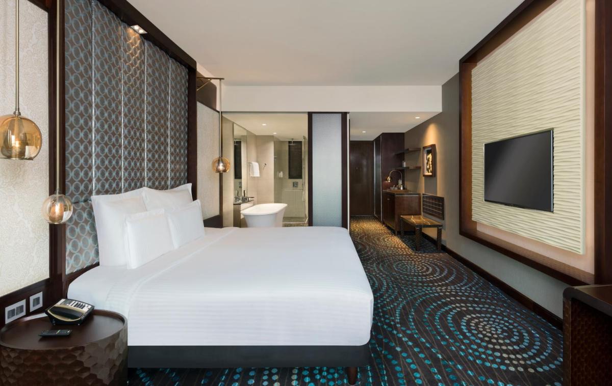 a hotel room with a large bed and a television at Pullman New Delhi Aerocity in New Delhi a hotel room with a large bed and a television at Pullman New Delhi Aerocity in New Delhi