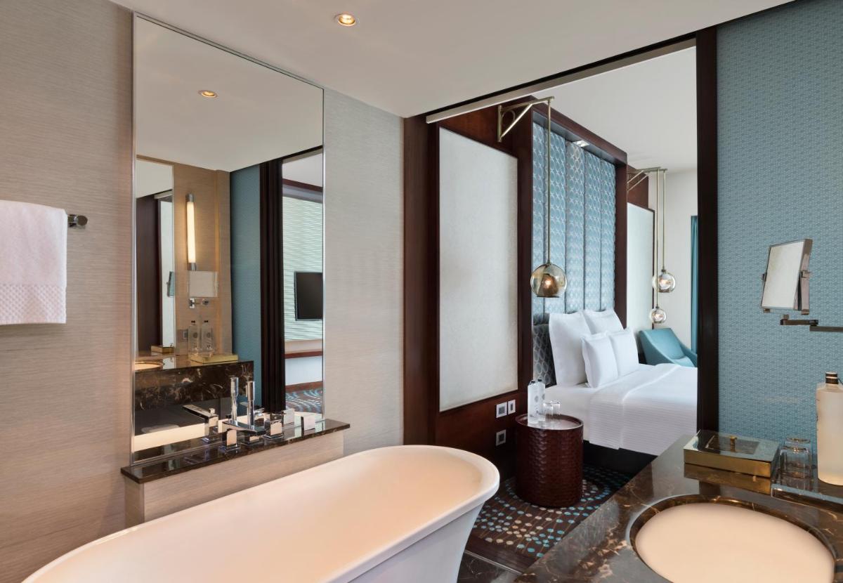 a bathroom with a tub and a bed and a mirror at Pullman New Delhi Aerocity in New Delhi a bathroom with a tub and a bed and a mirror at Pullman New Delhi Aerocity in New Delhi