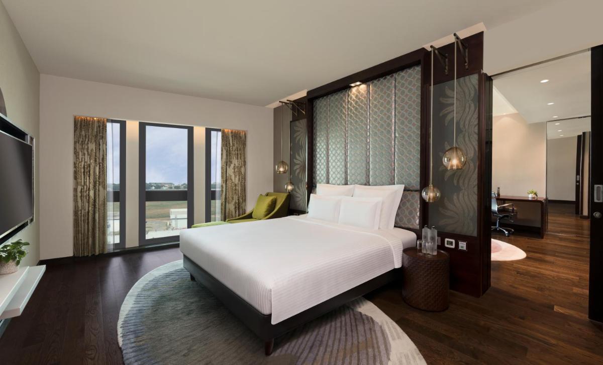a bedroom with a white bed and a large window at Pullman New Delhi Aerocity in New Delhi a bedroom with a white bed and a large window at Pullman New Delhi Aerocity in New Delhi
