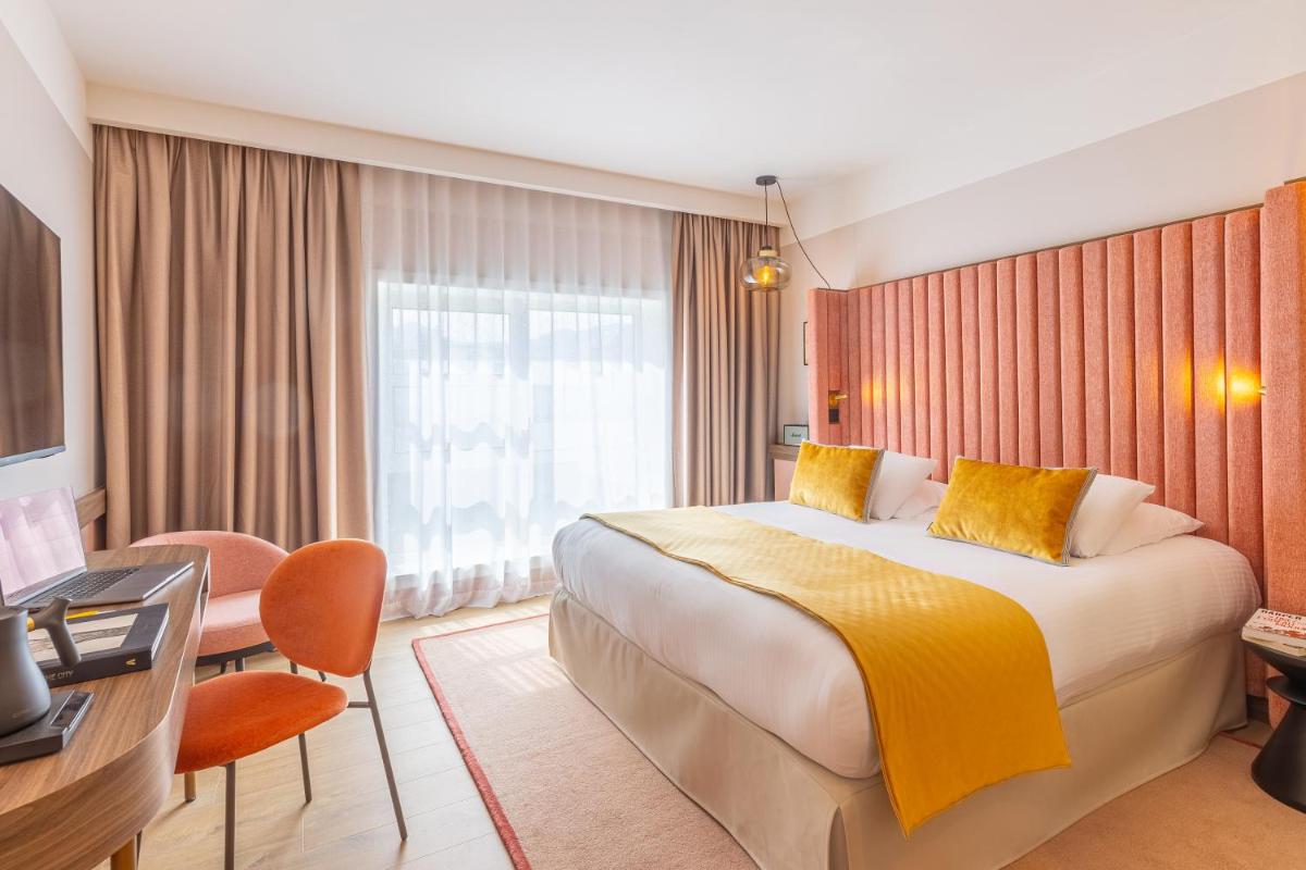 une chambre d'hôtel avec un lit et un bureau dans l'établissement Le Riviera - Hôtel Restaurant & Spa - Ex Golden Tulip Aix les bains, à Aix-les-Bains